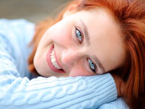 mulher ruiva sorrindo deitada com a cabeça no braço